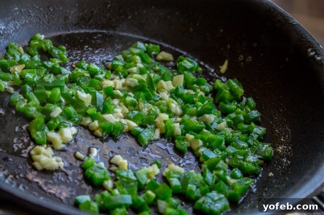 Garlic and finely chopped jalapeno sizzling in butter in a small skillet, releasing their aromatic flavors.