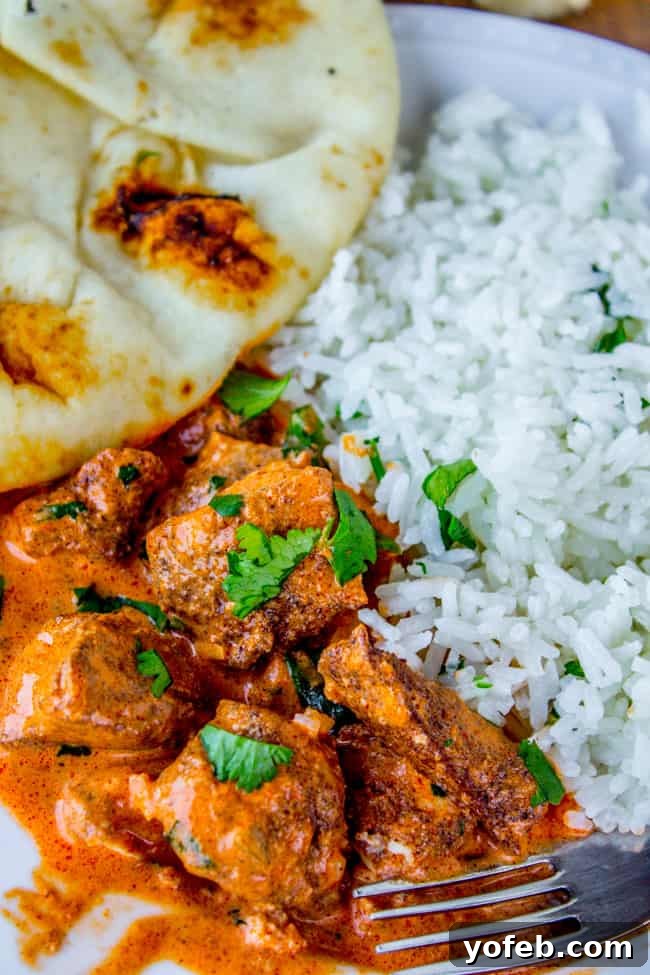A hearty serving of Slow Cooker Chicken Tikka Masala with jasmine rice and soft naan bread, garnished with fresh cilantro.