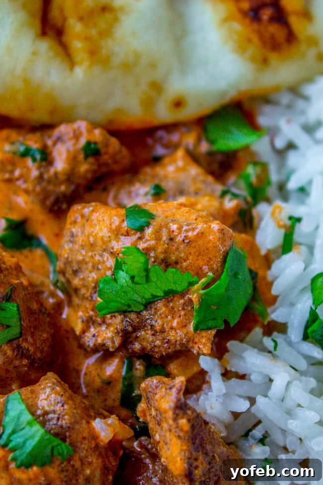 Delicious Slow Cooker Chicken Tikka Masala ready to be served, accompanied by rice and naan, with fresh cilantro for garnish.