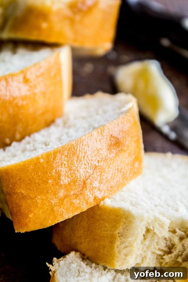 One Hour French Bread from The Food Charlatan. This delicious yeasty French bread recipe has only one 20-minute rise before going into a screaming hot oven for another 20 minutes. At the end you have golden crusty goodness just waiting to be slathered in butter or dipped in oil and balsamic! One hour, I promise!! #french #bread #homemade #easy #ideas #baguette #quick Several slices of homemade French bread arranged beautifully, with a softened stick of butter in the background, suggesting a delicious serving.