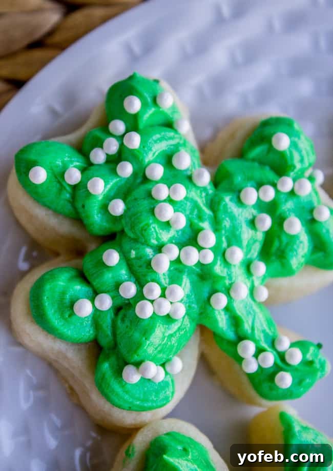 The Softest Sugar Cookies of Your Life from The Food Charlatan. A secret ingredient in this sugar cookies recipe makes these cookies the SOFTEST and most flavorful cookies of your life! And they even hold their shape after baking, so you get exactly what you want instead of sad blob cookies. #sugarcookies #cookies #frosting #soft #recipe #holiday #christmas #easter #halloween #fourthofjuly #stpatricksday #cookies #easy St. Patrick's Day sugar cookie with green frosting with sprinkles on top; close up.