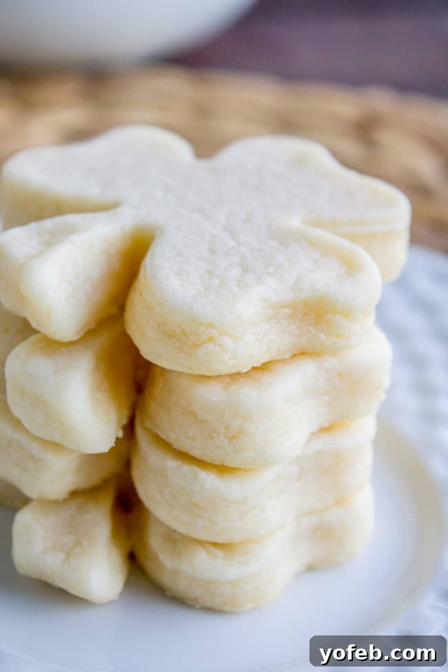 The Softest Sugar Cookies of Your Life from The Food Charlatan. A secret ingredient in this sugar cookies recipe makes these cookies the SOFTEST and most flavorful cookies of your life! And they even hold their shape after baking, so you get exactly what you want instead of sad blob cookies. #sugarcookies #cookies #frosting #soft #recipe #holiday #christmas #easter #halloween #fourthofjuly #stpatricksday #cookies #easy a stack of unfrosted shamrock-shaped cookies.