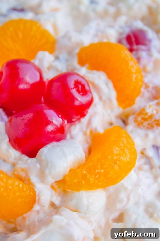 Heavenly Ambrosia Fruit Salad 2 A vibrant Ambrosia Salad featuring plump mandarin oranges, mini marshmallows, pecans, and coconut, served in an elegant glass bowl, perfect for Easter celebrations.