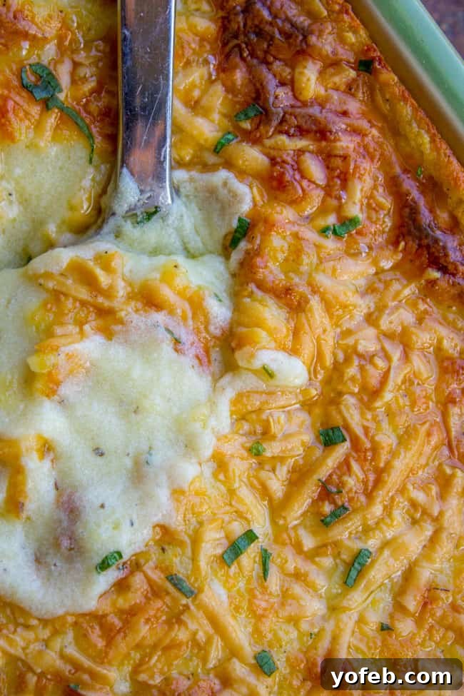 Ultimate Make Ahead Mashed Potatoes from Ina Garten 6 A large pan of golden-brown, cheesy make-ahead mashed potatoes with a serving spoon, freshly baked and ready.