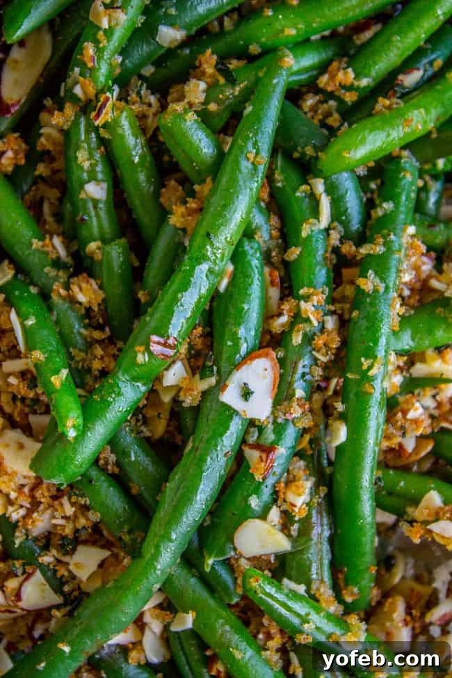 Freshly cooked green beans topped with golden garlic bread crumbs and toasted almonds, ready to be served.