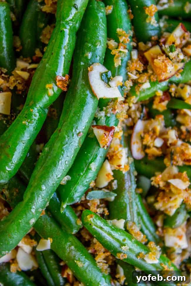 Serving platter of green beans topped with a generous amount of toasted almonds and garlic breadcrumbs.