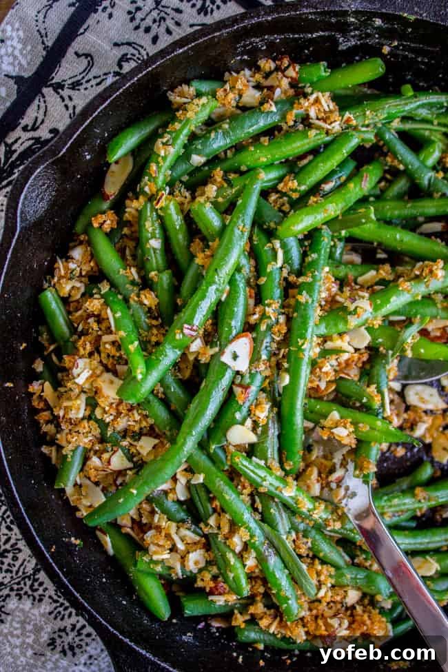 Green beans with garlic, almonds, and toasted breadcrumbs in a black pan, ready to be tossed.