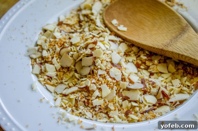 Sliced almonds and panko breadcrumbs toasting in a non-stick skillet over medium heat.