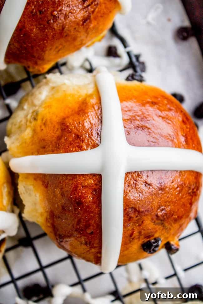 The Best Homemade Hot Cross Buns 2 A single perfectly baked hot cross bun on a cooling rack, showcasing its glossy cross.