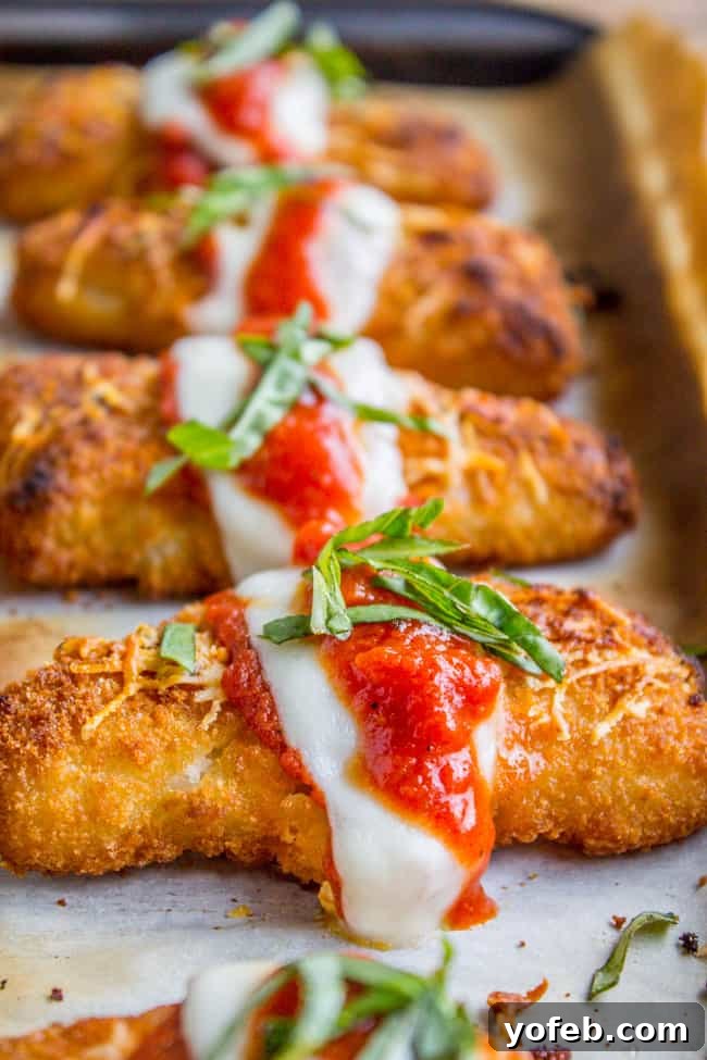 Crispy Fish Parmesan The Seafood Classic 2 Baked fish sticks topped with melted mozzarella, rich tomato sauce, and fresh basil on a sheet pan, ready for serving.