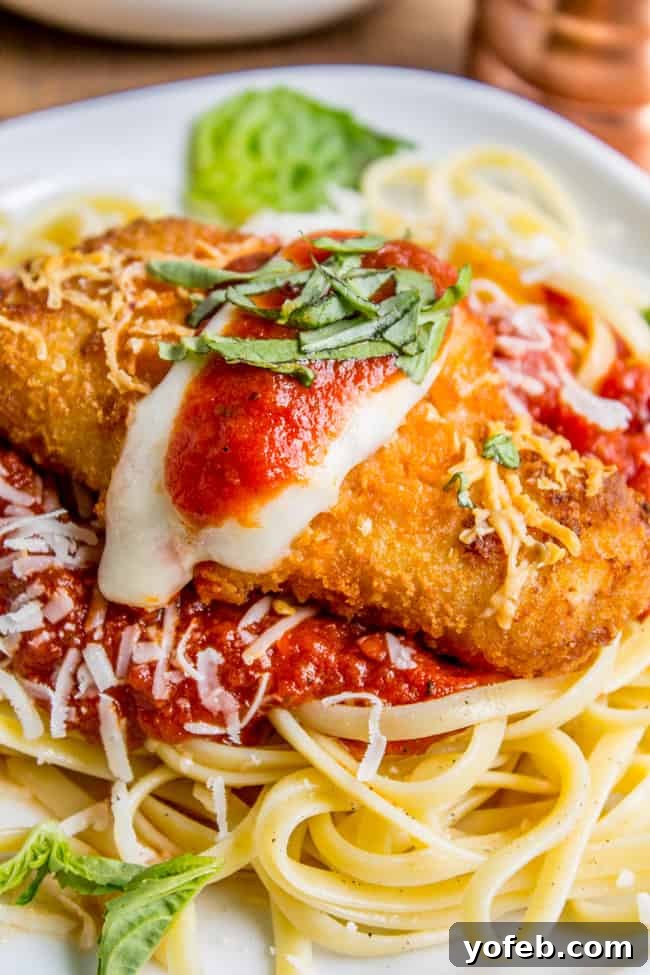 Crispy Fish Parmesan The Seafood Classic 3 A vibrant bowl of linguine pasta with marinara sauce, generously topped with crispy fish fillets, melted mozzarella, and fresh basil leaves.