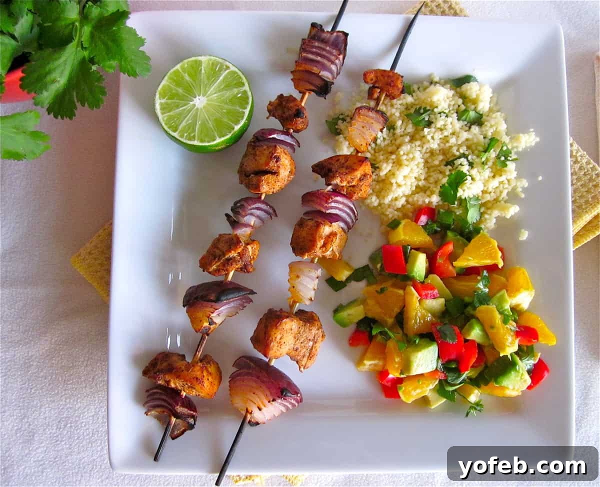 Chicken Kebabs with Orange Salsa Close-up of succulent chicken kebabs threaded with red onion, cooked to perfection, showcasing a golden-brown sear.