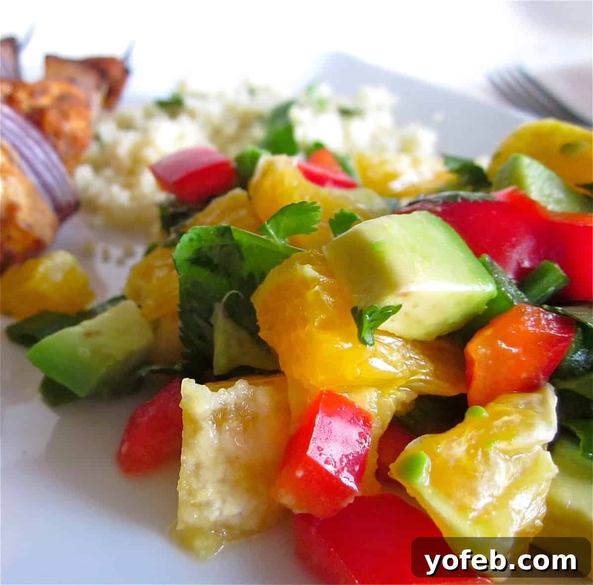 Vibrant Orange Salsa A serving of vibrant orange salsa with fresh herbs, red bell pepper, and avocado, ready to be paired with grilled chicken.