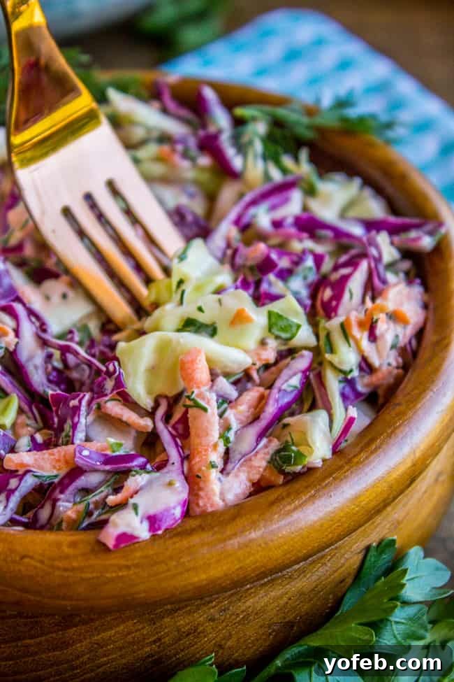 Zesty Lemon Herb Coleslaw 6 A rustic wooden bowl filled with creamy, lemon-herb coleslaw, with a fork resting inside, ready for serving.