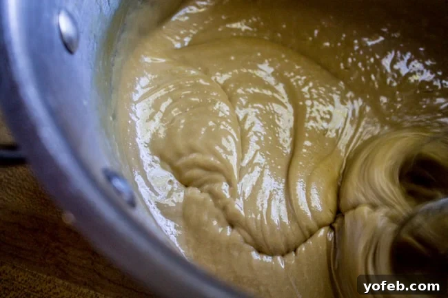 Velvet Peach Brown Sugar Dream 9 A hand mixer beating the brown sugar frosting in a metal bowl, showing its creamy, thickened texture.