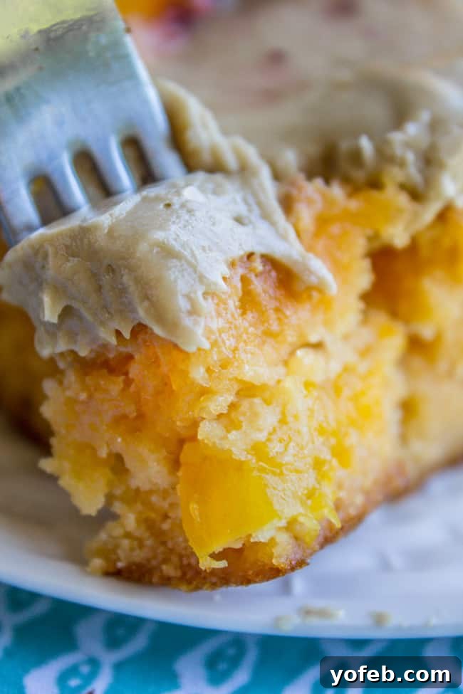 Velvet Peach Brown Sugar Dream 3 A close-up of a slice of peach cake, revealing its moist texture and pieces of real peach, topped with a generous swirl of brown sugar frosting.