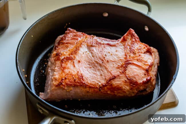Ultimate Corned Beef Slow Cooker or Oven 13 A thick cut of corned beef brisket perfectly seared to a golden-brown crisp in a hot pan, demonstrating excellent caramelization.