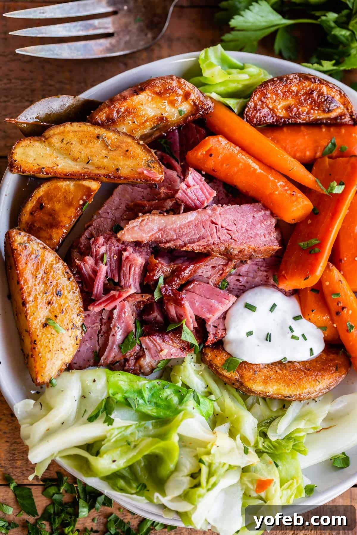 A beautifully plated dish of tender corned beef, vibrant green cabbage, roasted red potatoes, and sliced carrots, ready to be enjoyed.