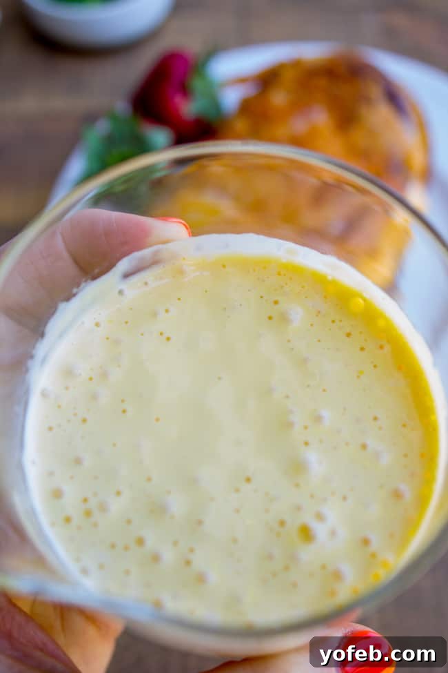 Easy Hollandaise Sauce Recipe: A close-up of the beautifully smooth and creamy blender hollandaise sauce in a white bowl.