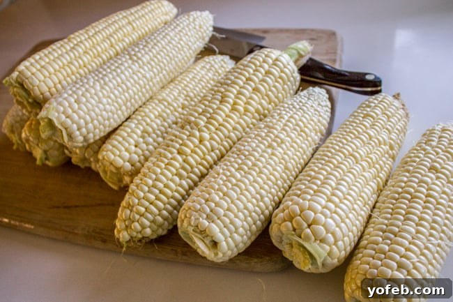 Mexican Street Corn Dip (Elote) from The Food Charlatan. This corn dip recipe is just like an elote (Mexican street corn). It is the perfect combo of sweet corn and savory tart cheese. Plus it's a lot easier to eat AND you get tortilla chips. Win! #corn #dip #elote #mexican #streetfood #summerfood #4thofjuly #cincodemayo #cotija #cornonthecob Fresh corn on the cob being prepped on a cutting board, ready for the Elote dip recipe.