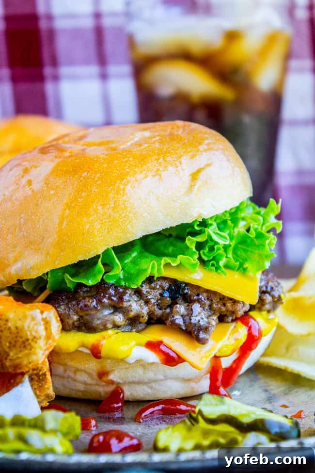 The Best Smash Burger Recipe (Cast Iron Skillet Burger) - Crispy Edges & Juicy Center A perfectly cooked smash burger with melted cheese, fresh lettuce, a slice of tomato, a drizzle of mustard, and a shiny, toasted bun.