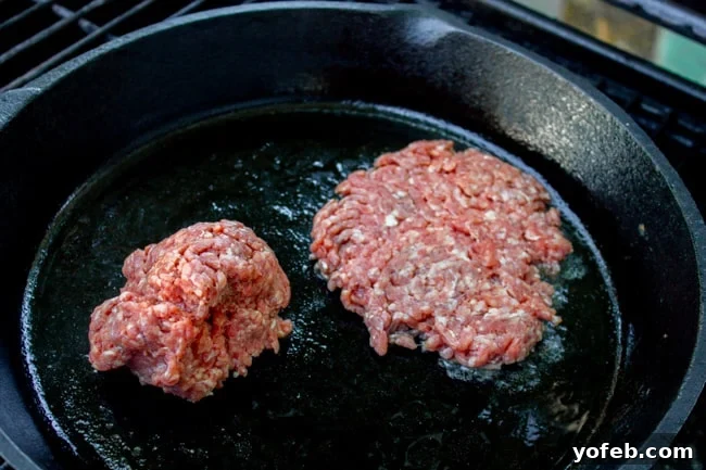 Ground Beef Balls on Cast Iron, Ready for Smashing Two balls of ground beef ready to be smashed on a sizzling hot cast iron skillet, capturing the anticipation of the cooking process.