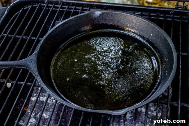 Cast Iron Skillet on Outdoor Grill for Burgers A cast iron skillet heating up on an outdoor grill, ready for smash burger preparation.