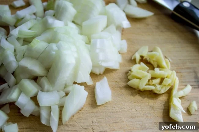Zucchini Velvet with a Pop of Corn 5 Chopped onions and garlic ready for sautéing on a wooden cutting board.