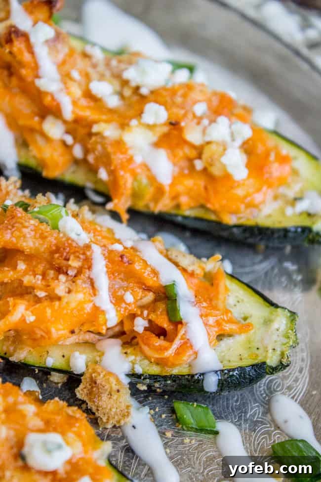 Fiery Buffalo Chicken Zucchini Boats 3 Close up of buffalo chicken in zucchini boat with scallions, crackers and ranch dressing.