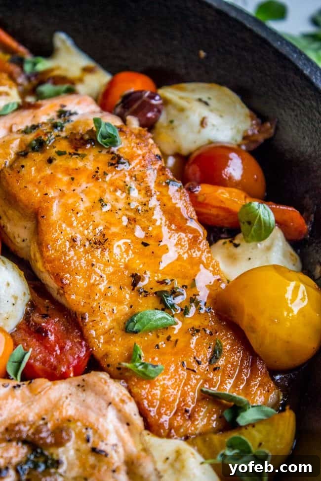 Speedy Pan-Seared Salmon with Burst Tomatoes and Melted Mozzarella 3 Close-up of a pan-seared salmon fillet garnished with cherry tomatoes and mozzarella, hinting at a delicious, healthy meal.