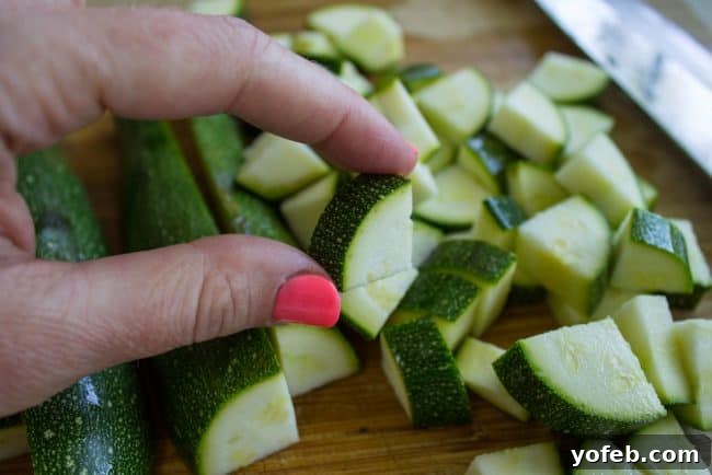 Effortless 10-Minute Zucchini Squash Side 5 Freshly diced green zucchini pieces, uniformly cut into small chunks, spread across a wooden cutting board, ready for sautéing.