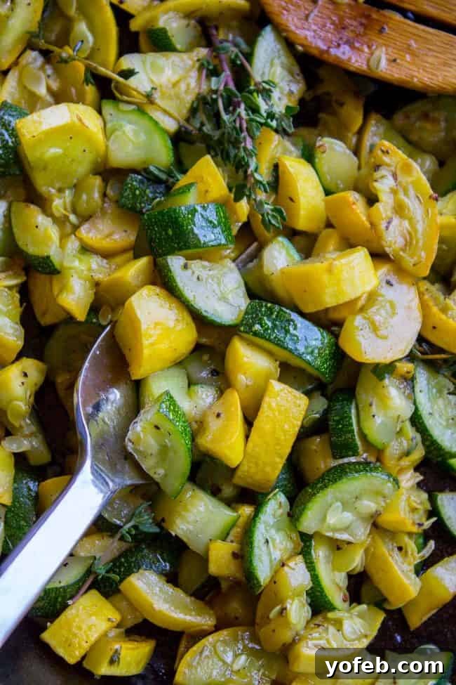 Effortless 10-Minute Zucchini Squash Side 6 Close-up of vibrant green zucchini and yellow squash chunks sautéing in a pan with fragrant thyme, being stirred by a wooden spoon.