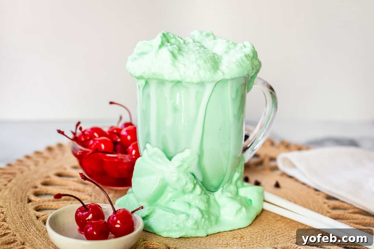 Leprechaun's Delight Shake 14 An overflowing glass mug, with Shamrock Shake spilled all around it on the surface, next to a small bowl of maraschino cherries. A humorous accident during photo taking.