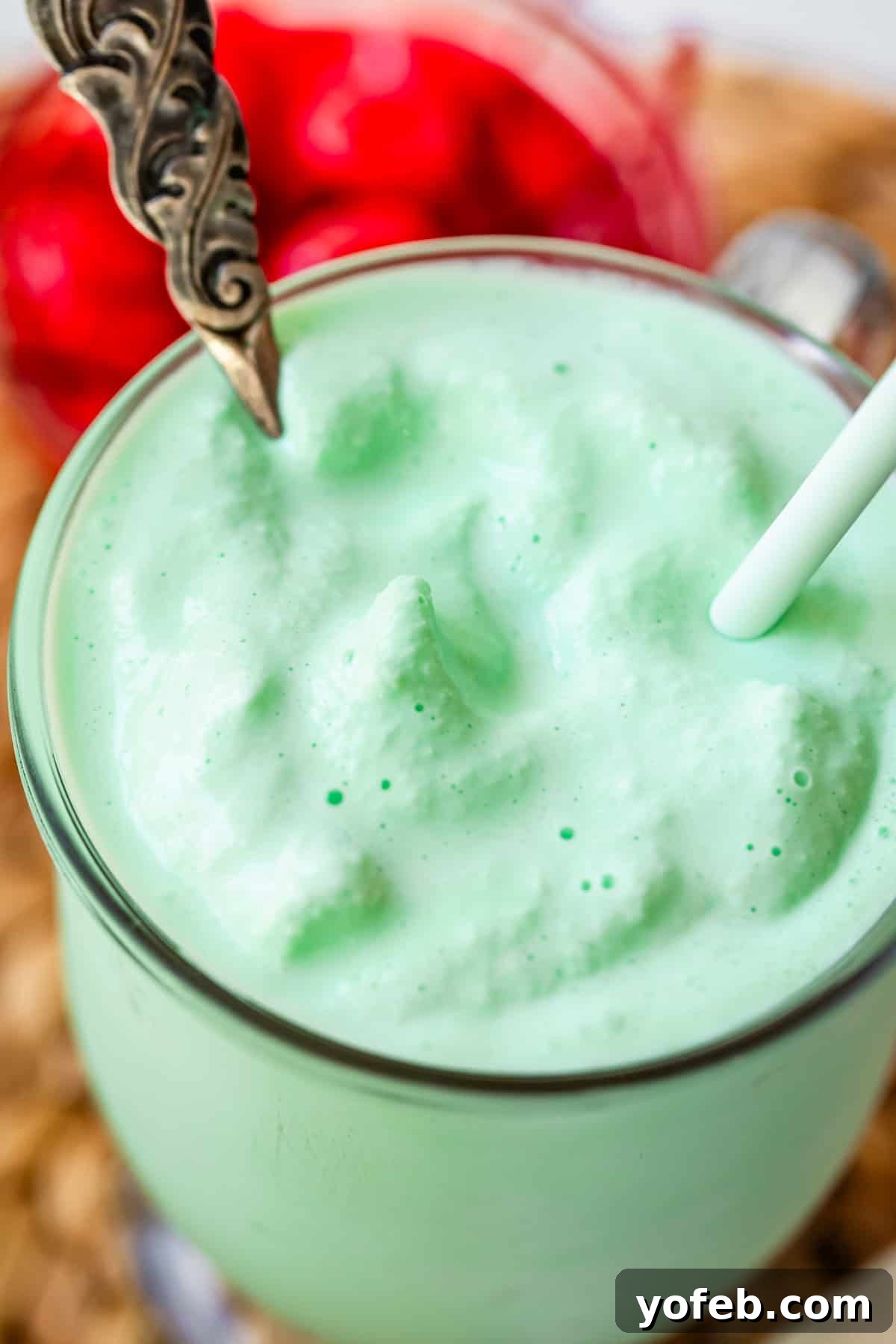 Leprechaun's Delight Shake 19 A frosty glass mug filled with a vibrant green Shamrock Shake, complete with a spoon and a straw, signalling a delicious treat.