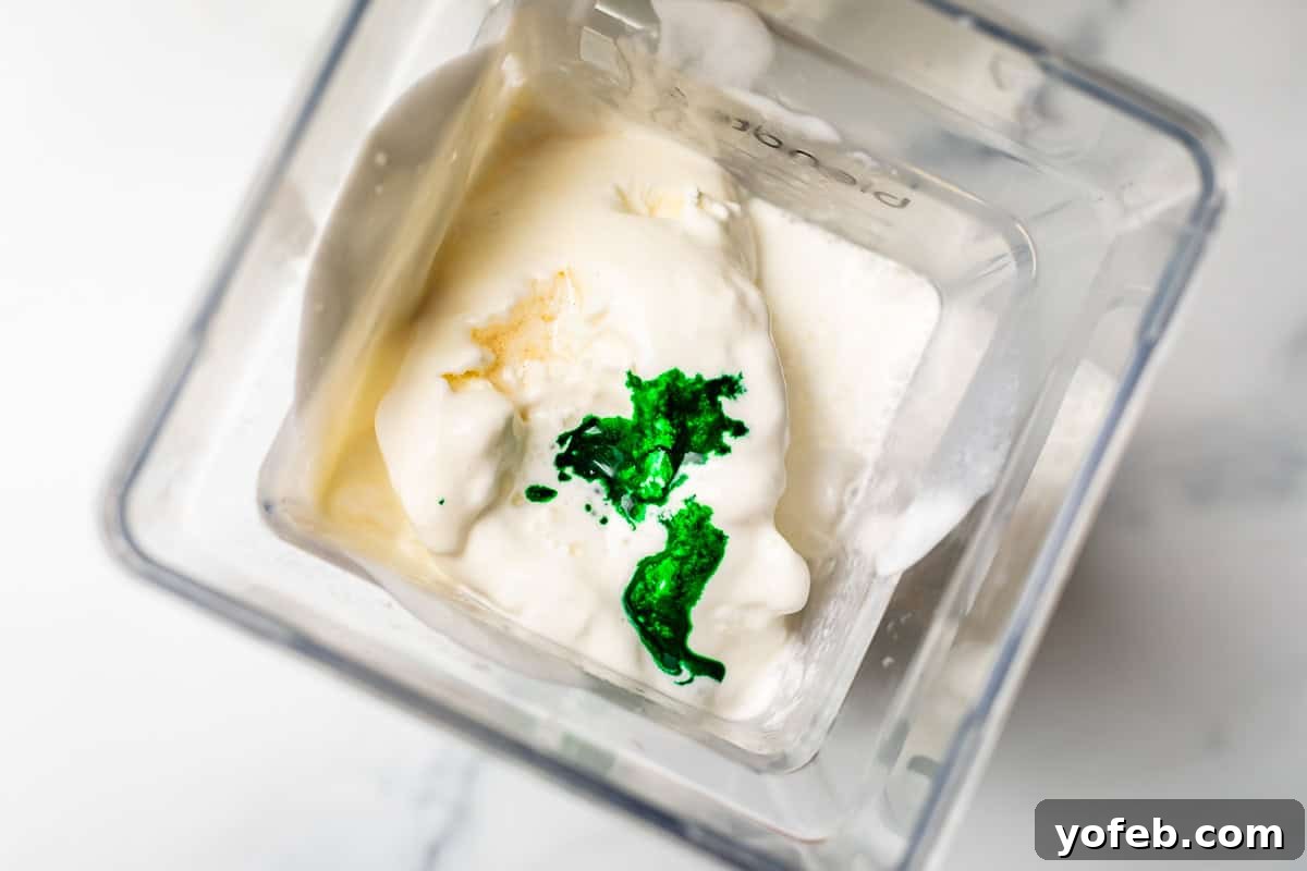 Leprechaun's Delight Shake 9 A top-down view into a blender, showing green food coloring drops drizzled over the vanilla ice cream, ready for blending.