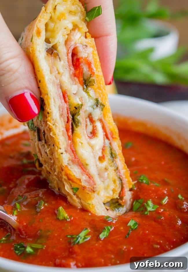The Ultimate Homemade Stromboli 3 Manicured hand dipping stromboli slice in marinara sauce.