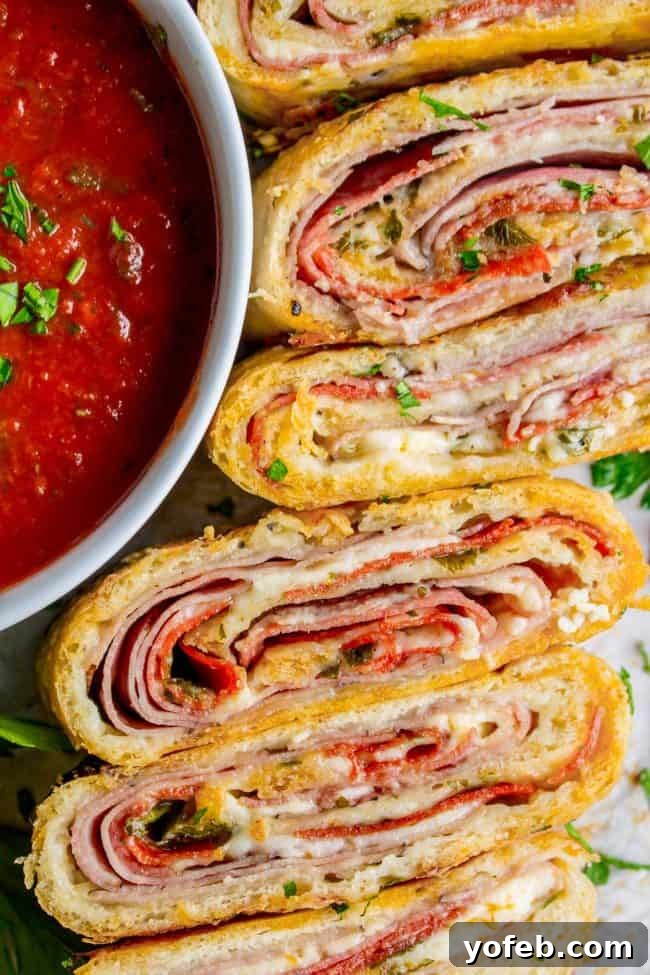 The Ultimate Homemade Stromboli 5 sliced stromboli with meat, cheese, and fresh parsley next to a bowl of marinara sauce.