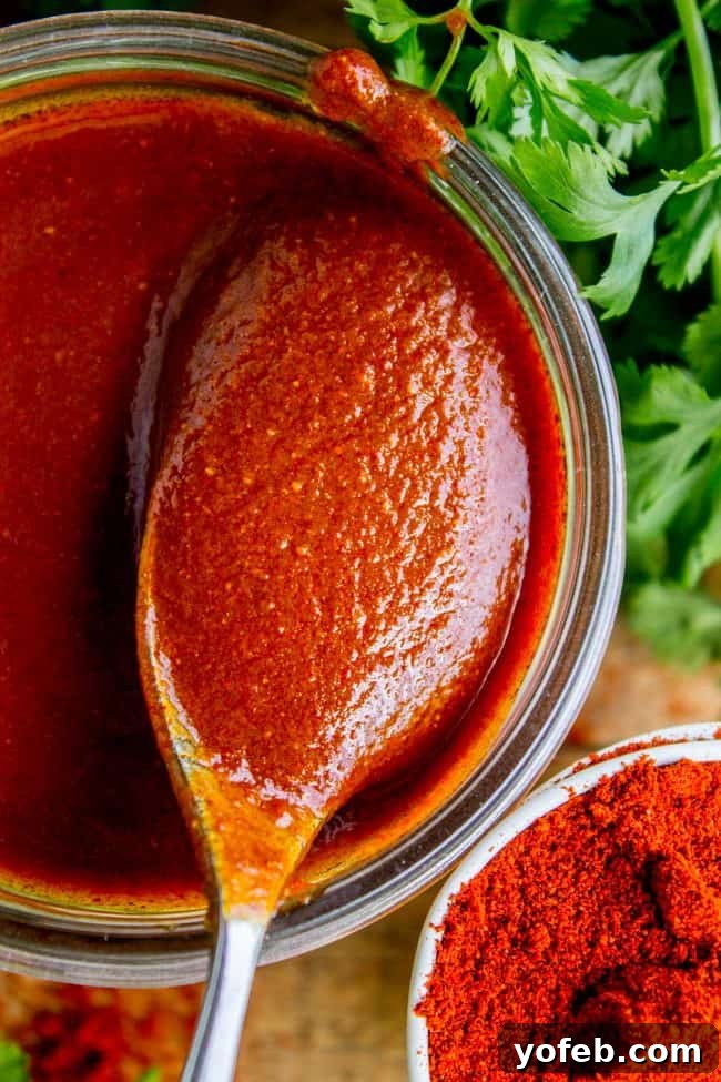 Speedy Homemade Enchilada Sauce 9 A charming mason jar filled with vibrant red enchilada sauce, garnished with fresh parsley sprigs, ready for serving or storage.