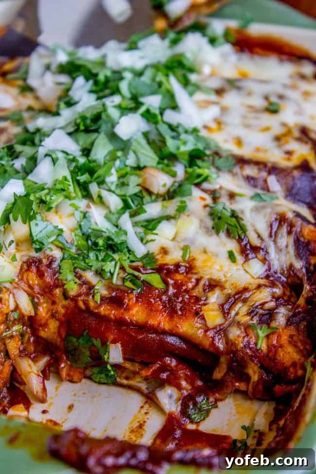 A baking dish of sweet potato and black bean enchiladas with a slice already removed, showcasing the rich filling and melted cheese.