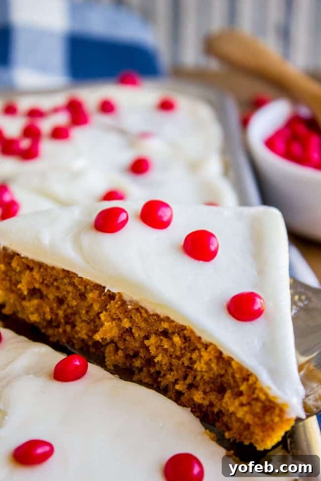 Decadent Pumpkin Squares with Cream Cheese Frosting 4 A perfectly sliced pumpkin bar topped with generous cream cheese frosting and cinnamon red hots, showcasing its moist texture.