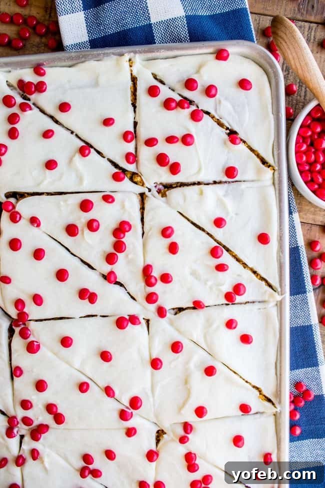 Decadent Pumpkin Squares with Cream Cheese Frosting 6 A sheet pan filled with golden pumpkin bars, freshly frosted with cream cheese and topped with bright red hots.