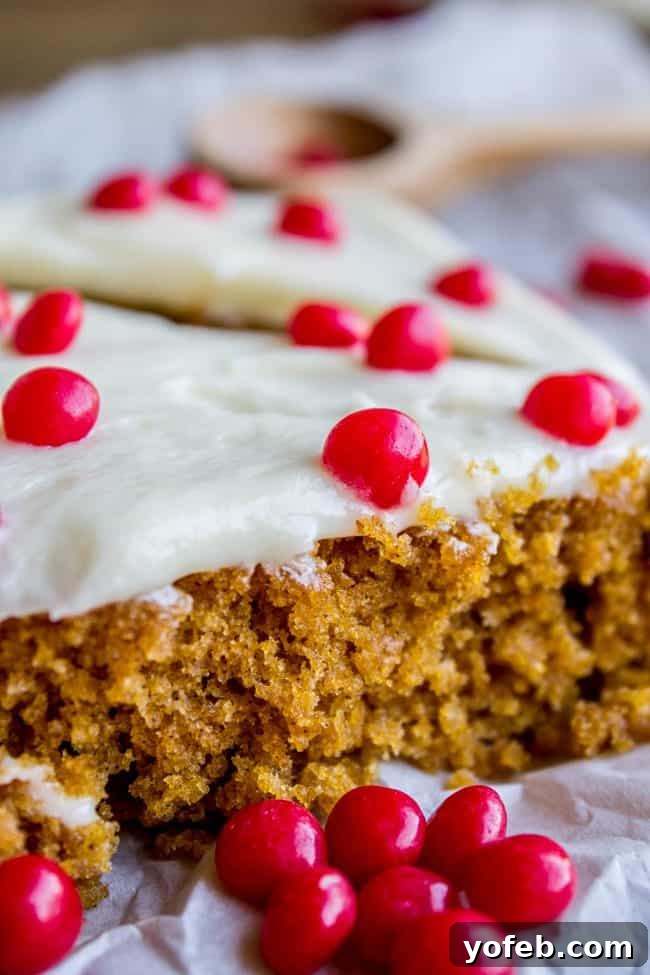 Decadent Pumpkin Squares with Cream Cheese Frosting 5 Close-up of a single pumpkin bar with cream cheese frosting and a scattering of vibrant red hots, inviting a delicious bite.
