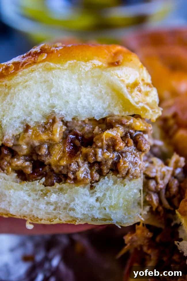 Irresistible Mini Burgers 4 Close-up of a cheesy burger slider on a soft Hawaiian roll, ready to be eaten.