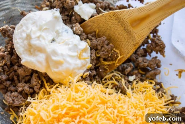 Irresistible Mini Burgers 5 Mixing cooked ground beef with mayonnaise and shredded cheddar cheese in a bowl.