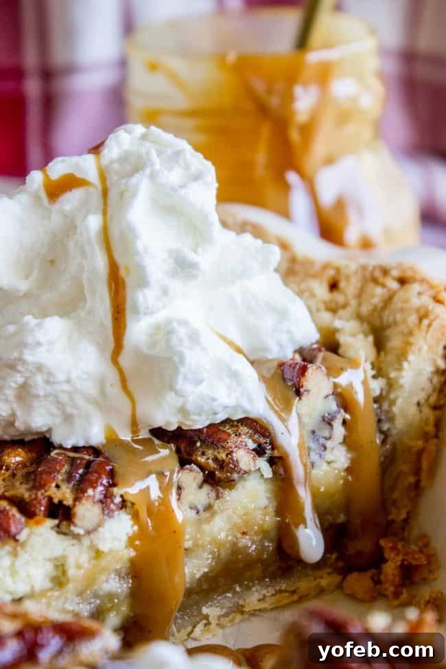 Decadent Pecan Cheesecake Pie 10 A perfectly cut slice of Cheesecake Pecan Pie, showcasing its distinct layers, served with generous amounts of whipped cream and caramel sauce on a white plate.