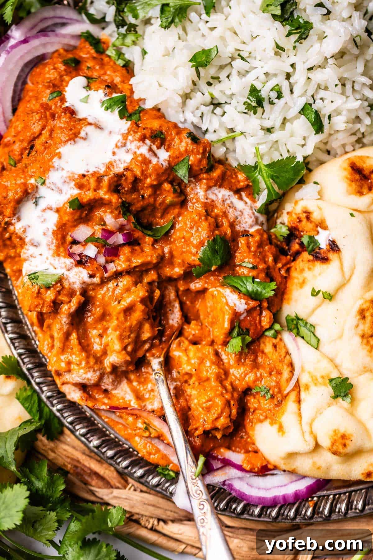 Chicken Tikka Masala A Culinary Revelation 3 looking down on a metal tray with a serving of rice, naan, and tikka masala with a spoon.
