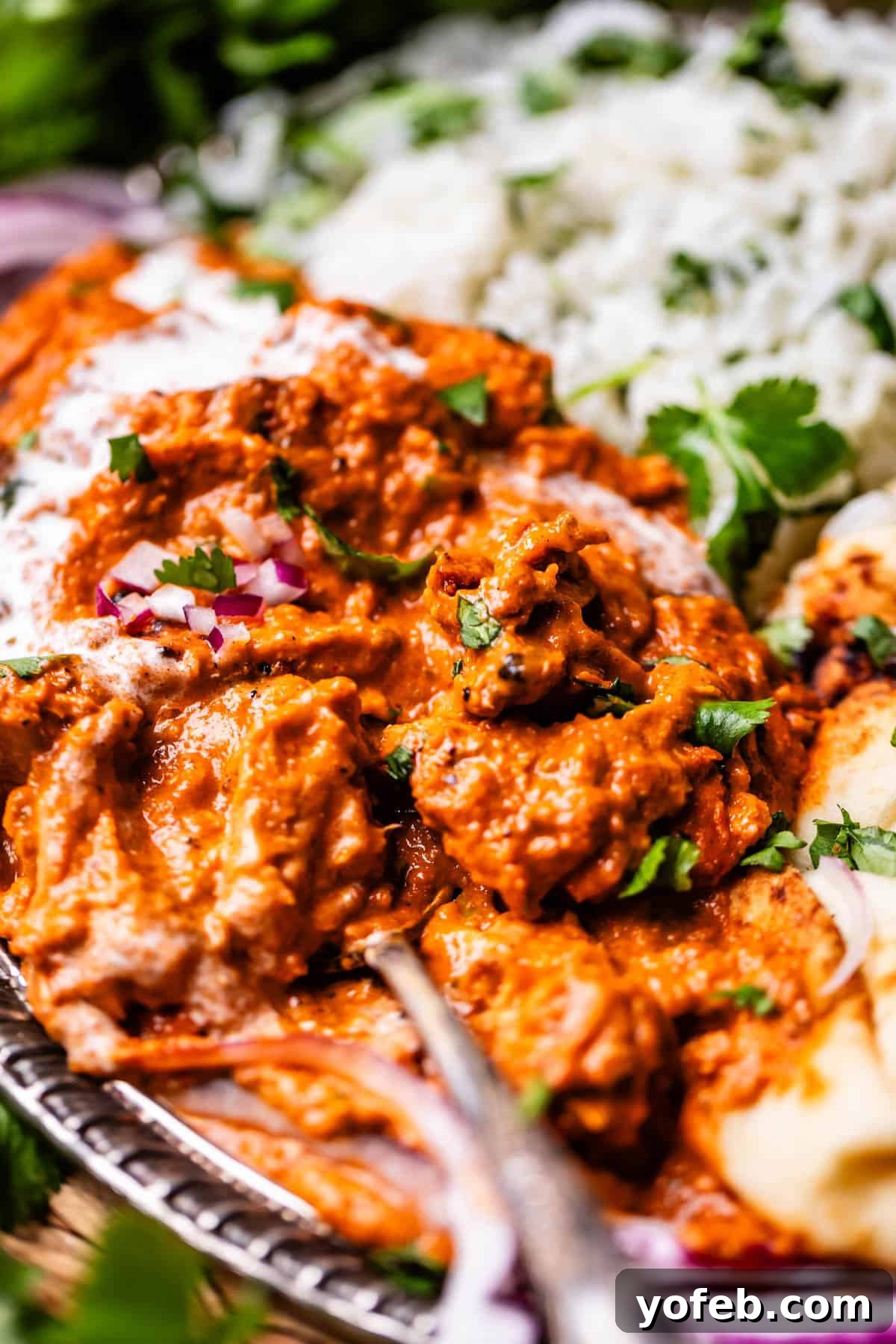 Chicken Tikka Masala A Culinary Revelation 21 side view of a metal tray of chicken tikka masala with rice and naan sides.