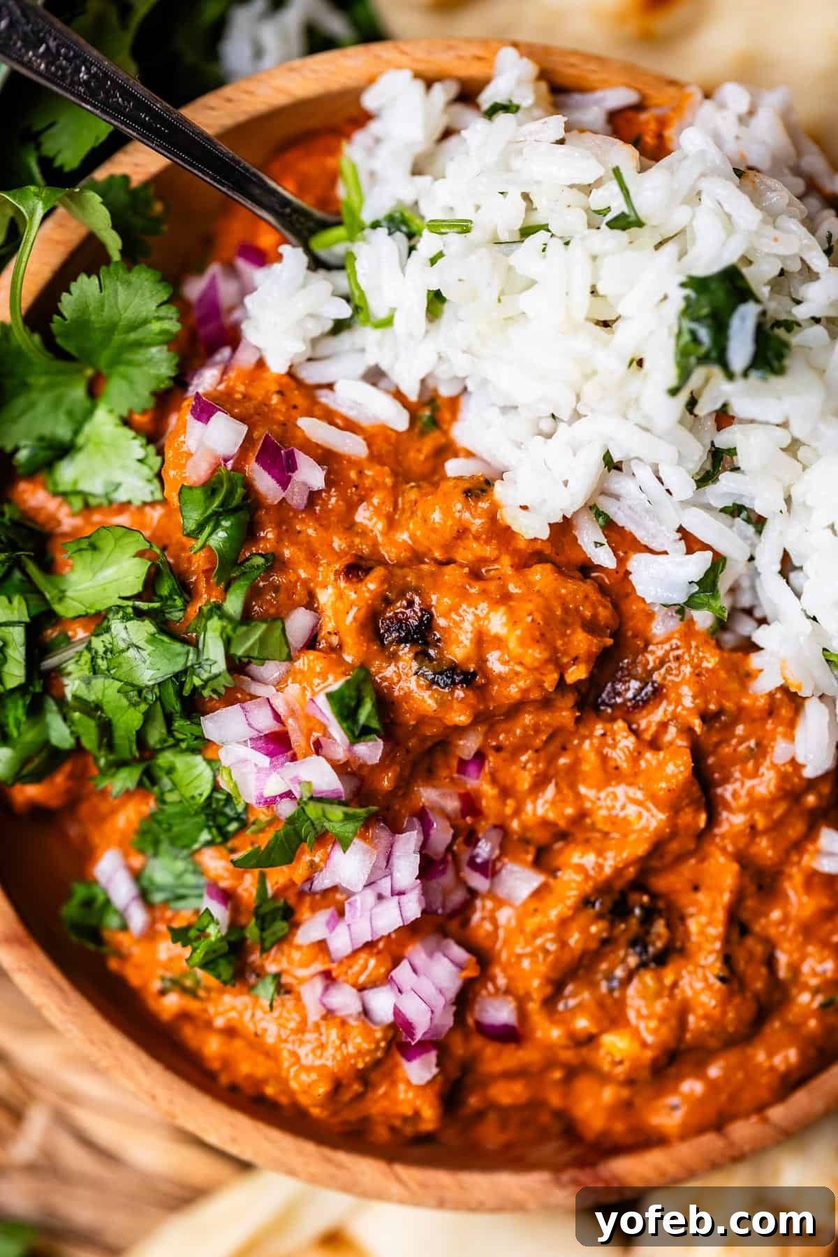 Chicken Tikka Masala A Culinary Revelation 4 wooden bowl filled with chicken tikka masala and rice with red onion and cilantro garnish.