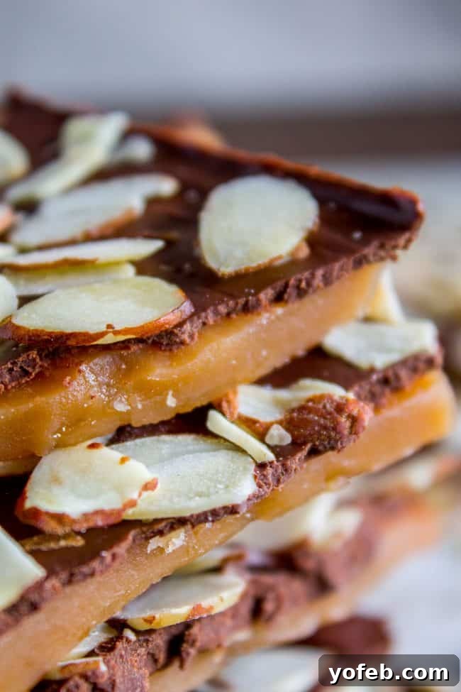 The Best Homemade English Toffee Recipe by The Food Charlatan. This is the BEST homemade English Toffee Recipe, hands down! This is such an easy and QUICK treat to make for the Christmas holidays. You don't even need a candy thermometer! #toffee #English #candy #Christmas #easy #homemade #tutorial #recipe #almonds Homemade English toffee with almonds stacked in a very close-up shot, showcasing its irresistible layers.