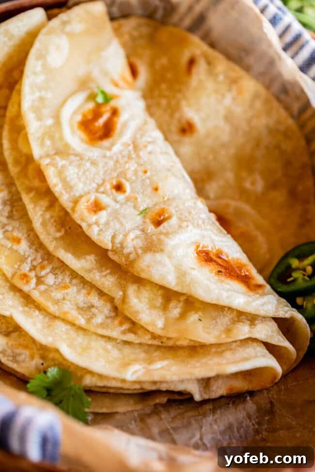 Roti Buttery Indian Flatbread Perfection 12 soft roti recipe folded over in parchment paper with cilantro.